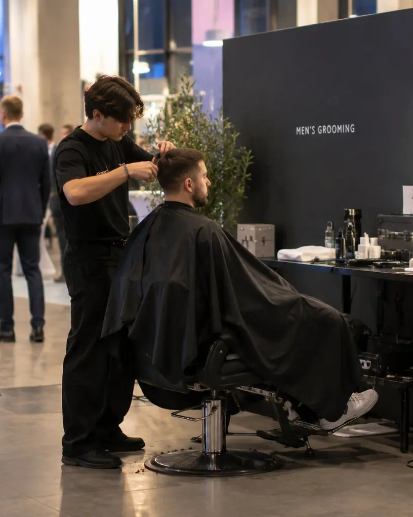 Barber schneidet an einer Grooming-Station auf einem Abendevent einem Gast die Haare – Live-Barber für Brand Activations