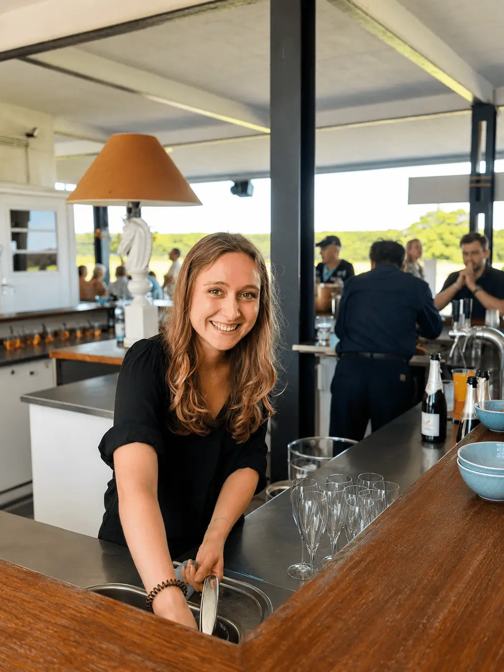 Server smiling behind the counter of a bright summer venue