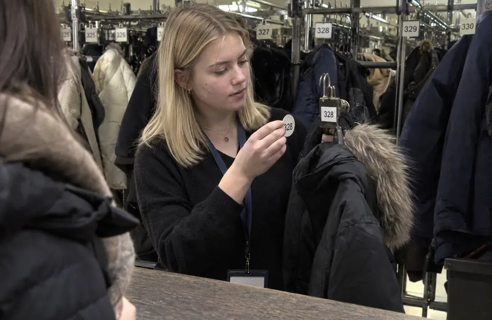 Garderobenkraft gleicht die Garderobenmarke 328 mit der Nummer am Bügel einer Winterjacke ab