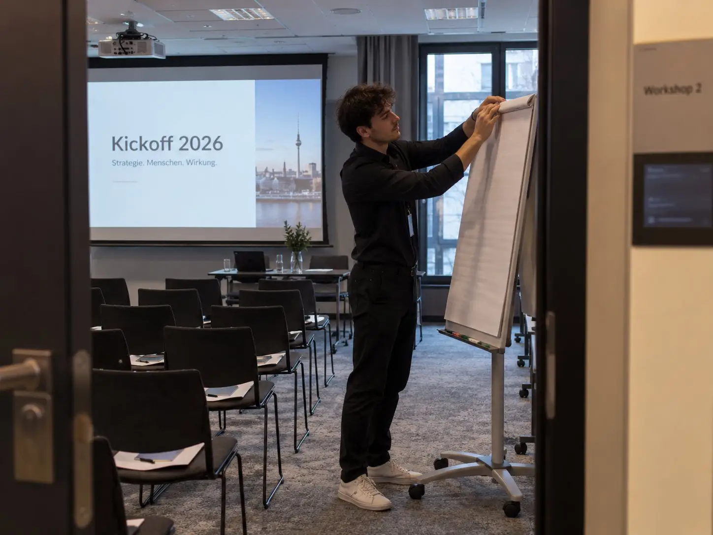 Host prepares a flipchart in a workshop room before a kick-off conference